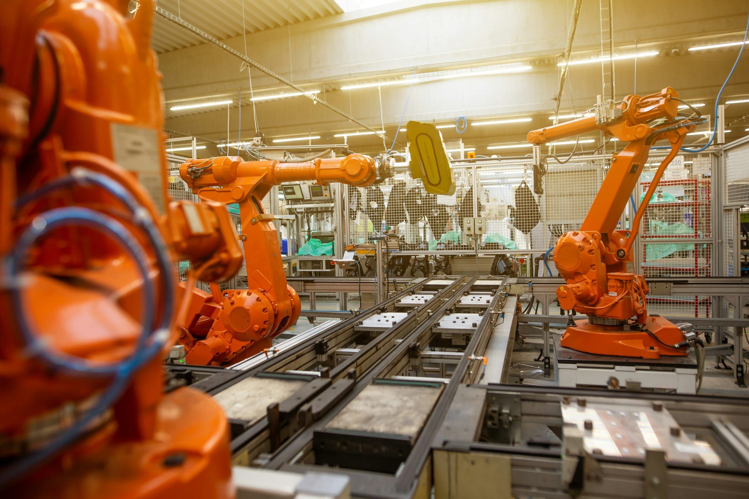 A row of orange industrial robot arms over a production line